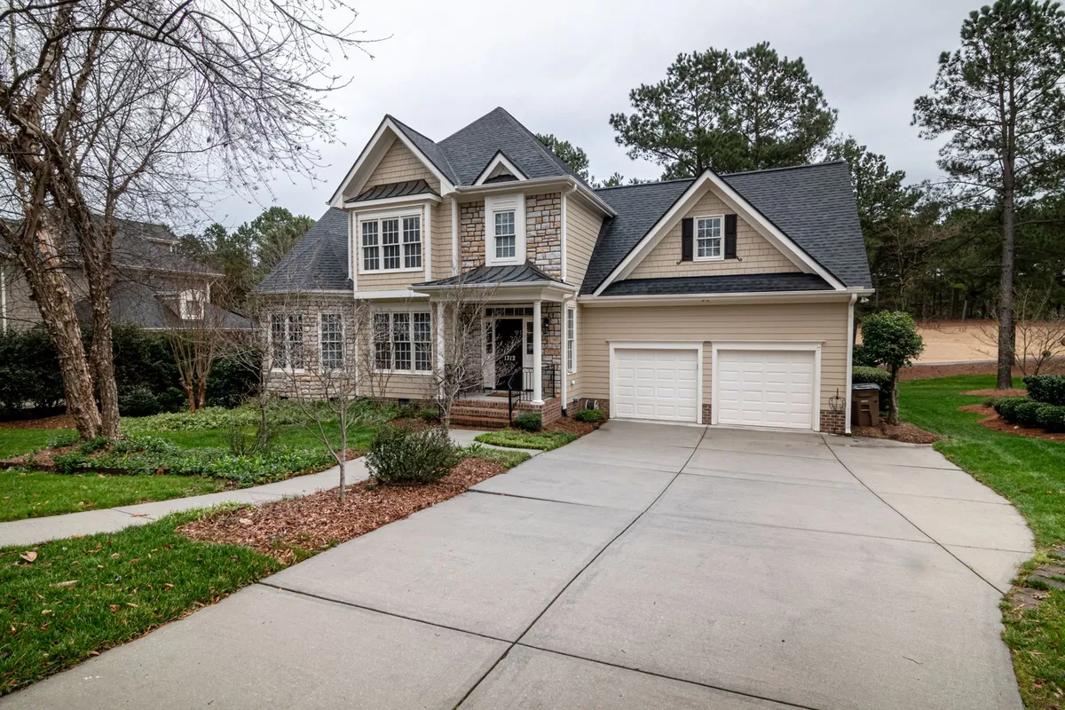 A two-story suburban family home with a charcoal architectural shingle roof, a double garage and a long driveway